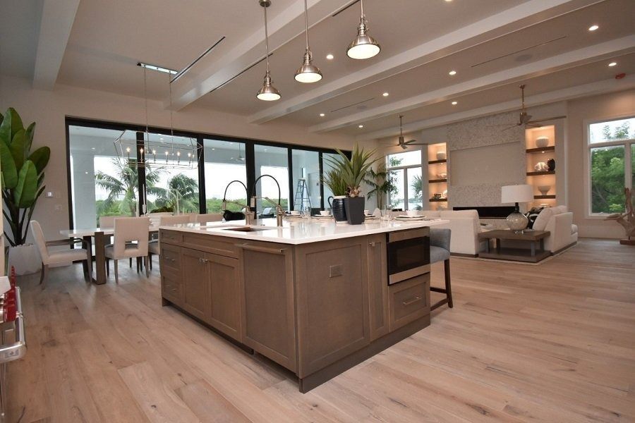 Large open-plan kitchen with island, dining area, and living room with floor-to-ceiling windows.