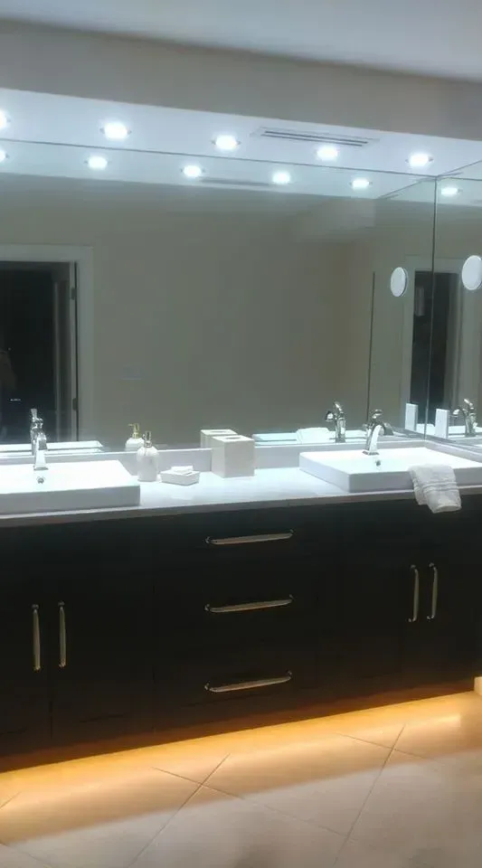 Bathroom with double sinks, large mirror, black vanity, and overhead lighting.