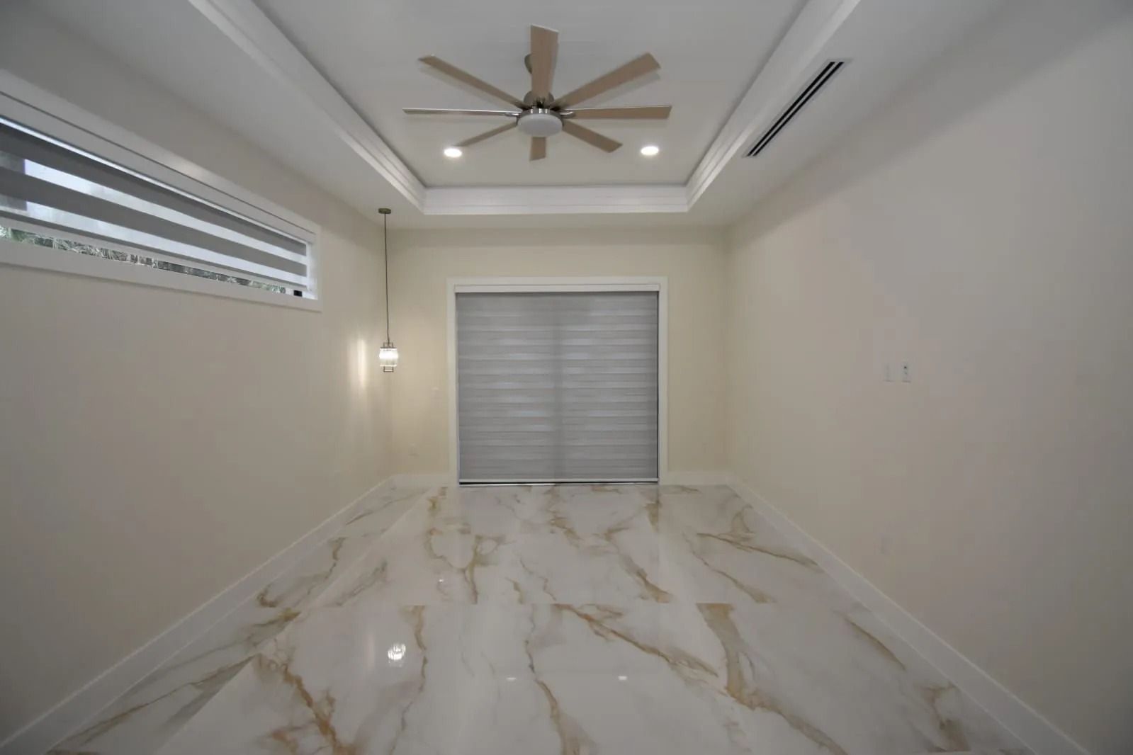 Empty room with marble floors, off-white walls, and a ceiling fan.
