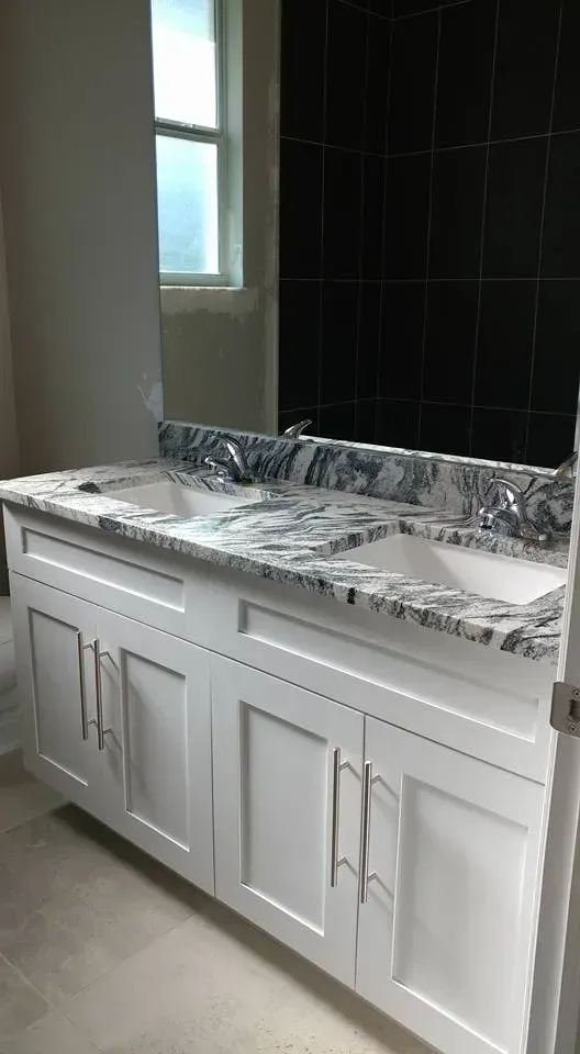 White double sink bathroom vanity with granite countertop and black tile wall.