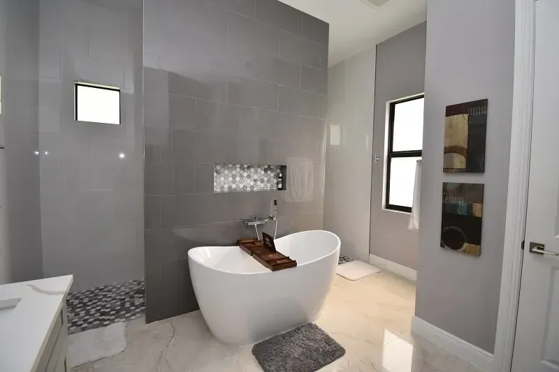 Modern gray bathroom with a freestanding tub, tile walls, and artwork.