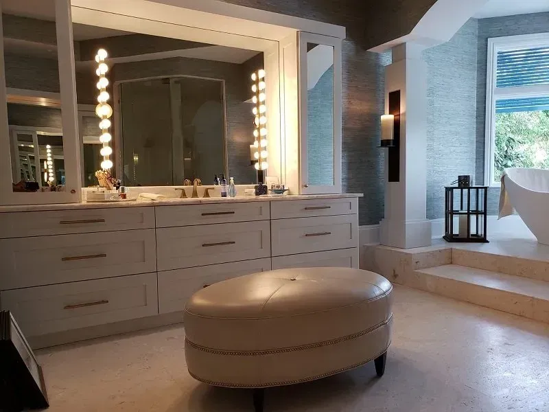 Elegant bathroom with vanity, large mirror, and oval ottoman. 