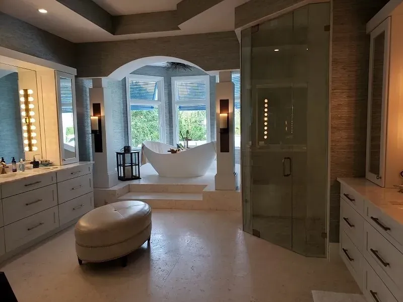 Spacious luxury bathroom with a bathtub, glass shower, vanity, and large windows. 