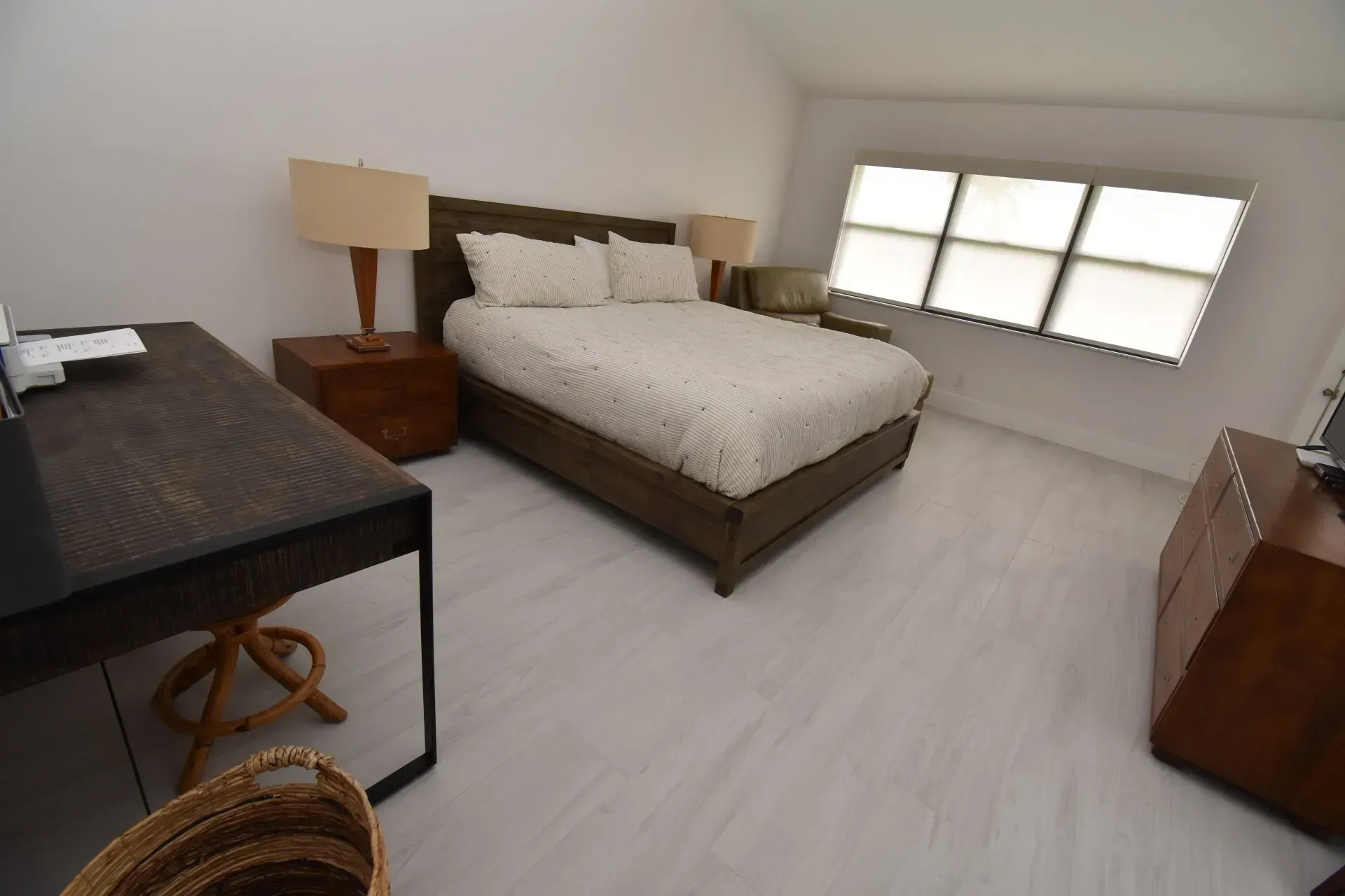 Bedroom with bed, desk, two nightstands with lamps, and a window. 