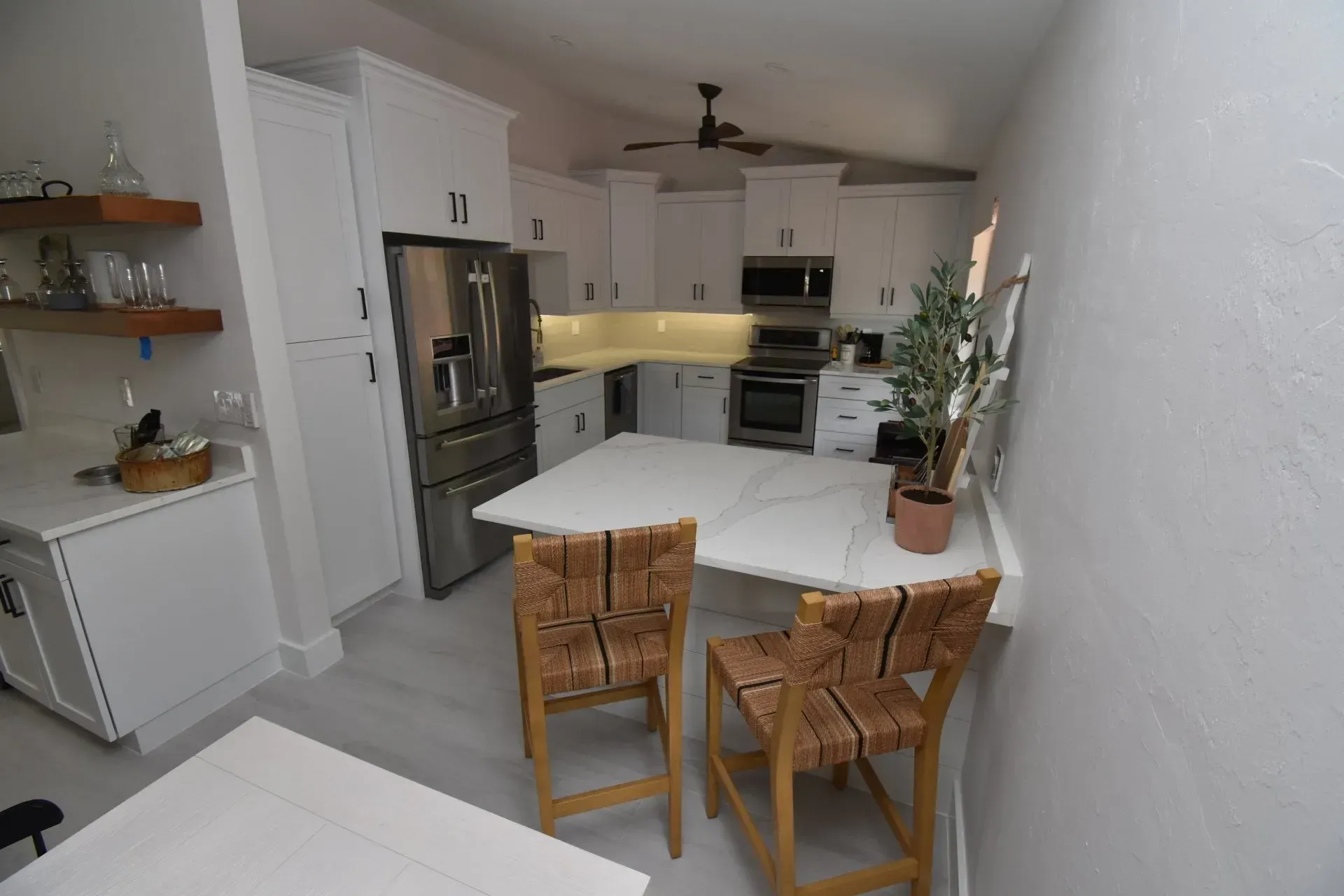 White kitchen with island and two woven bar stools. 