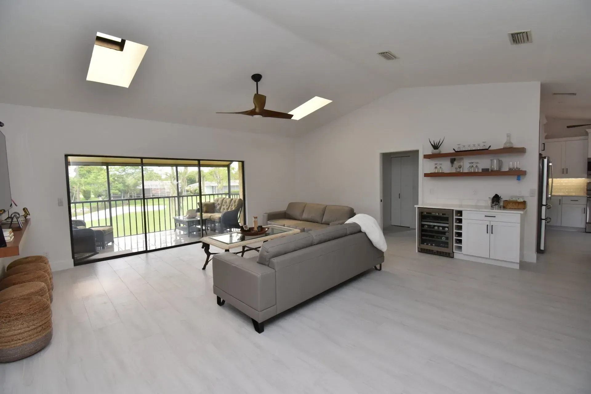 Living room with gray sofa, sliding glass doors, white walls, and skylights.