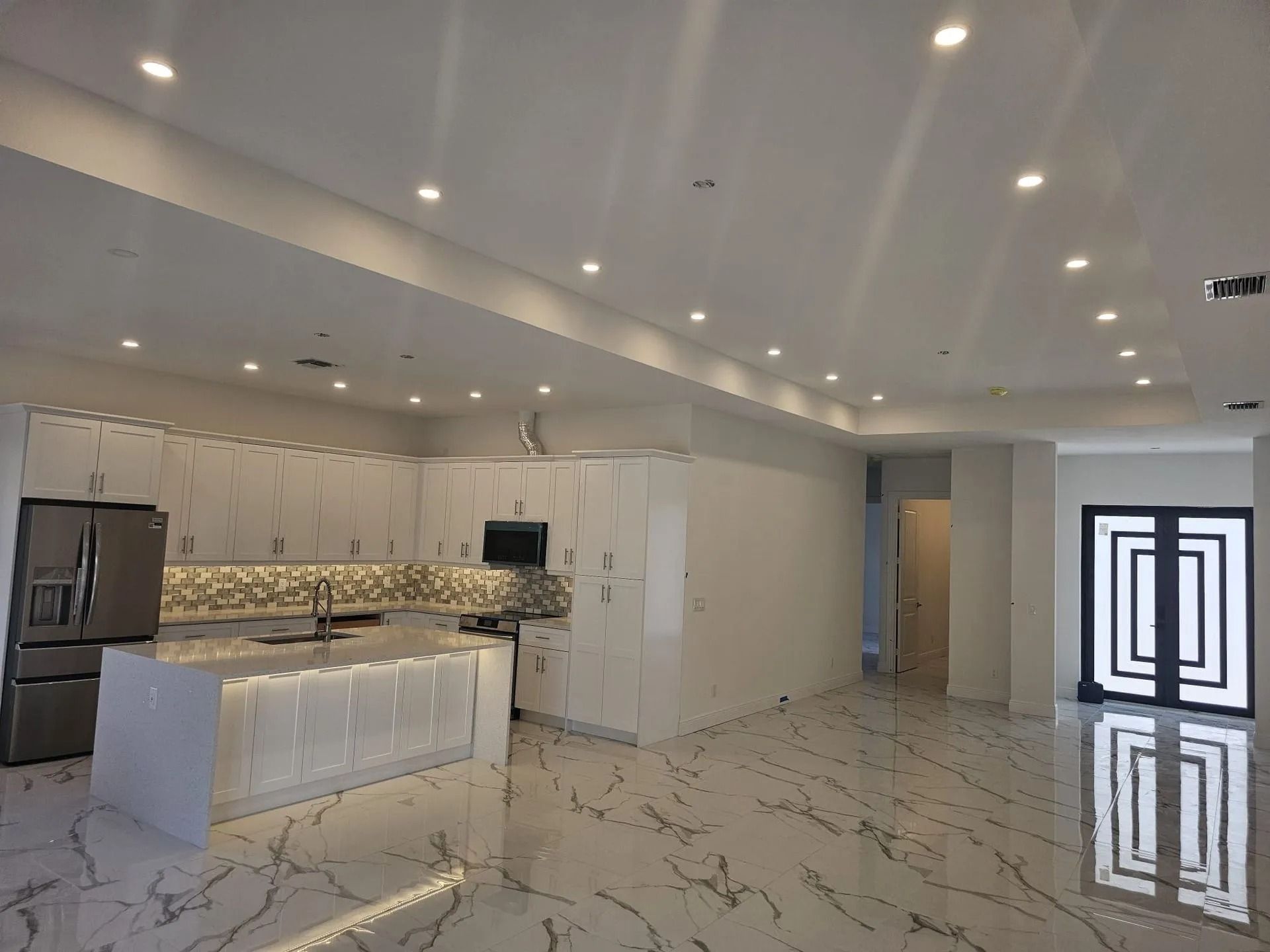 Modern kitchen with white cabinets, marble countertops, and tile floor.