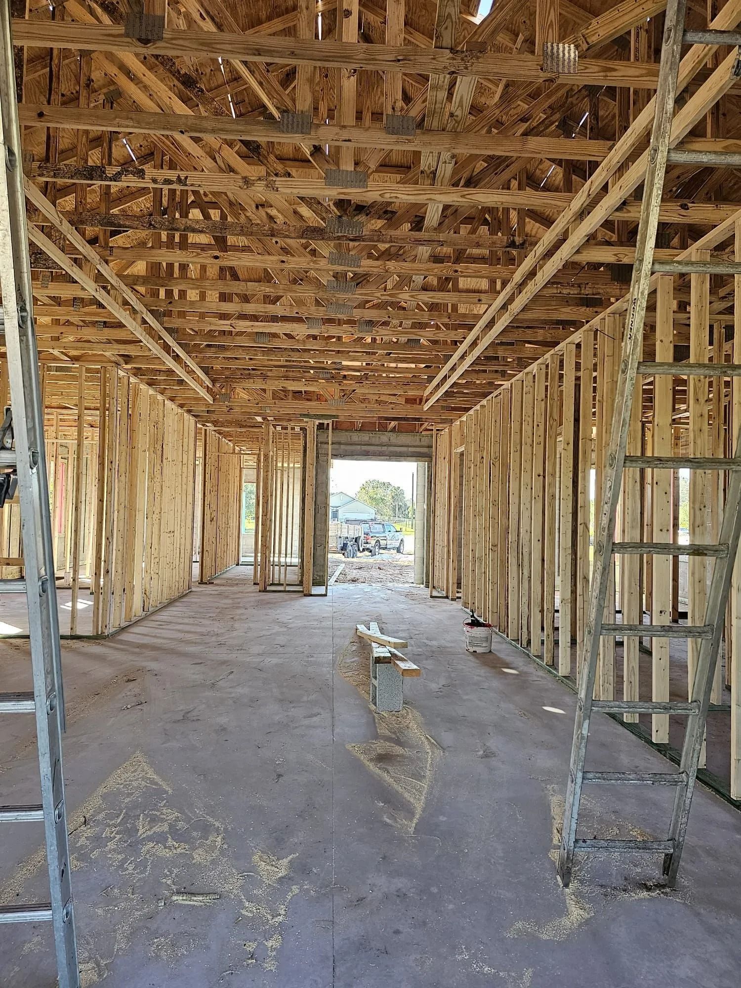Interior view of a building under construction with wood framing, two ladders, and a doorway.