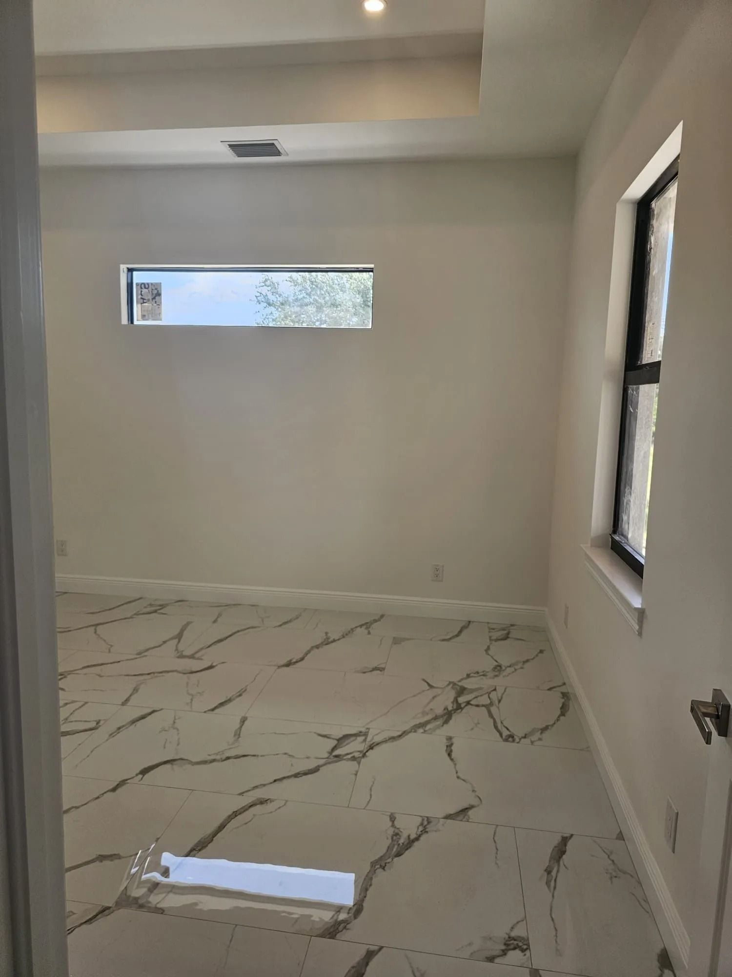 Empty room with marble floors, white walls, and two windows.