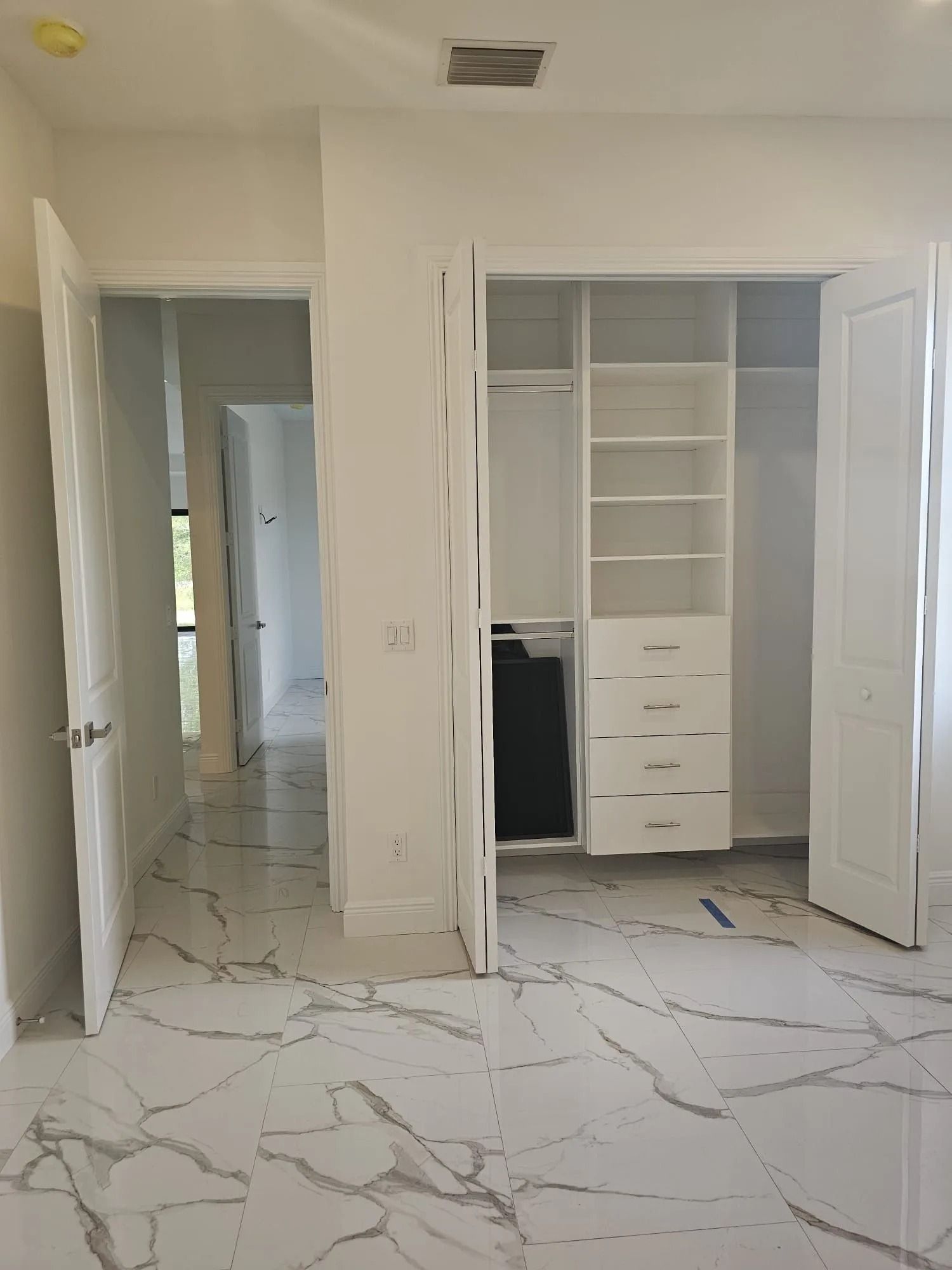 Bedroom with marble floors, open closet, and doorway leading to another room.
