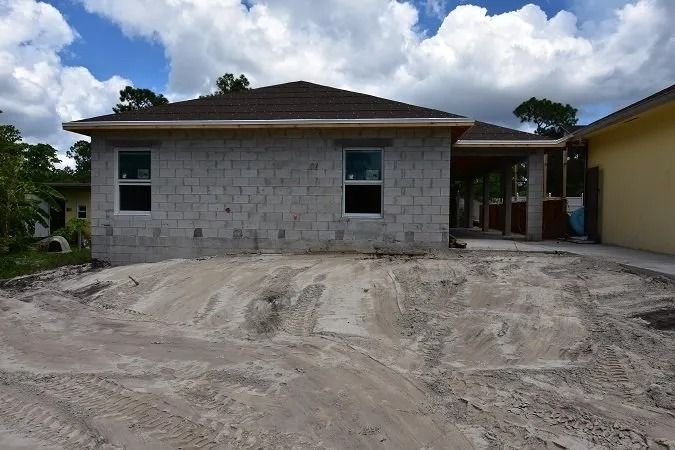 Gray block house under construction with sand in front.
