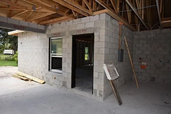 Unfinished concrete block building interior with open doorway and window, under construction.