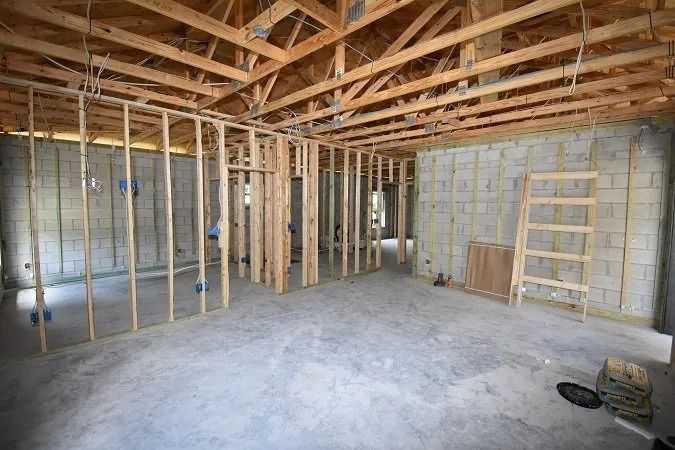 Interior of a building under construction with wooden framing, concrete block walls, and exposed rafters.