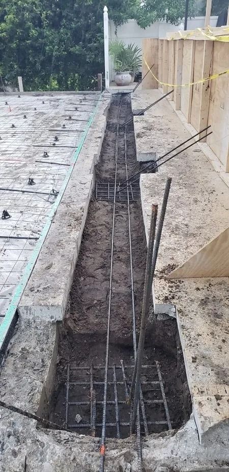 Construction site with a trench containing rebar framework, ready for concrete.