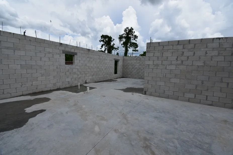 Construction site with concrete block walls, a concrete floor, and a cloudy sky.