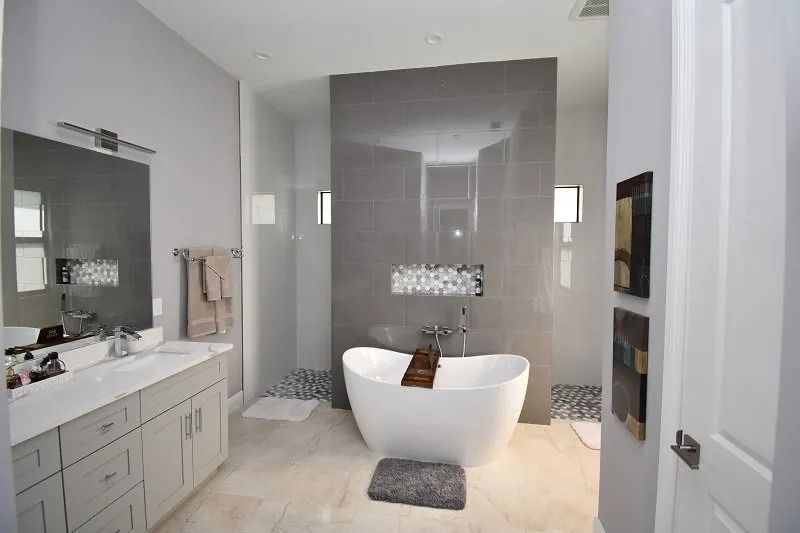 Modern gray bathroom with a freestanding tub, vanity, and large mirror.