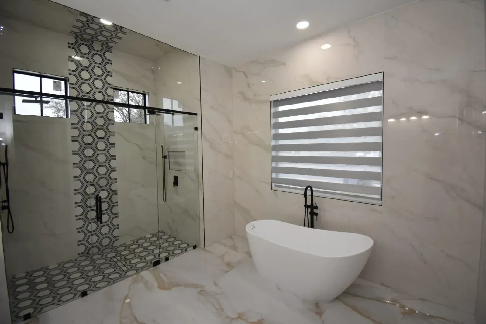 Luxurious bathroom with marble walls and a standalone tub.