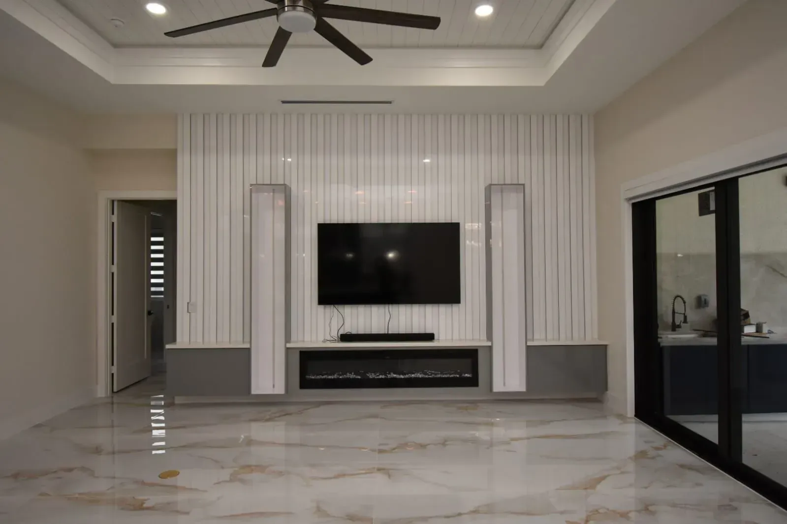 Living room with a mounted TV above an electric fireplace, flanked by tall vertical panels.