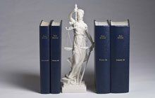 A statue of justice standing next to three books.