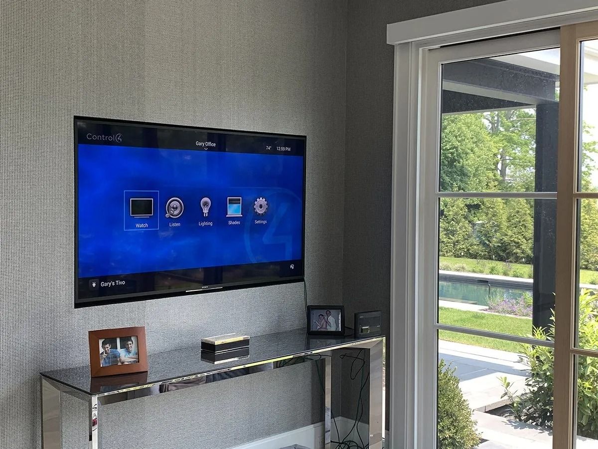 TV mounted on textured wall, console below, window with outdoor view.