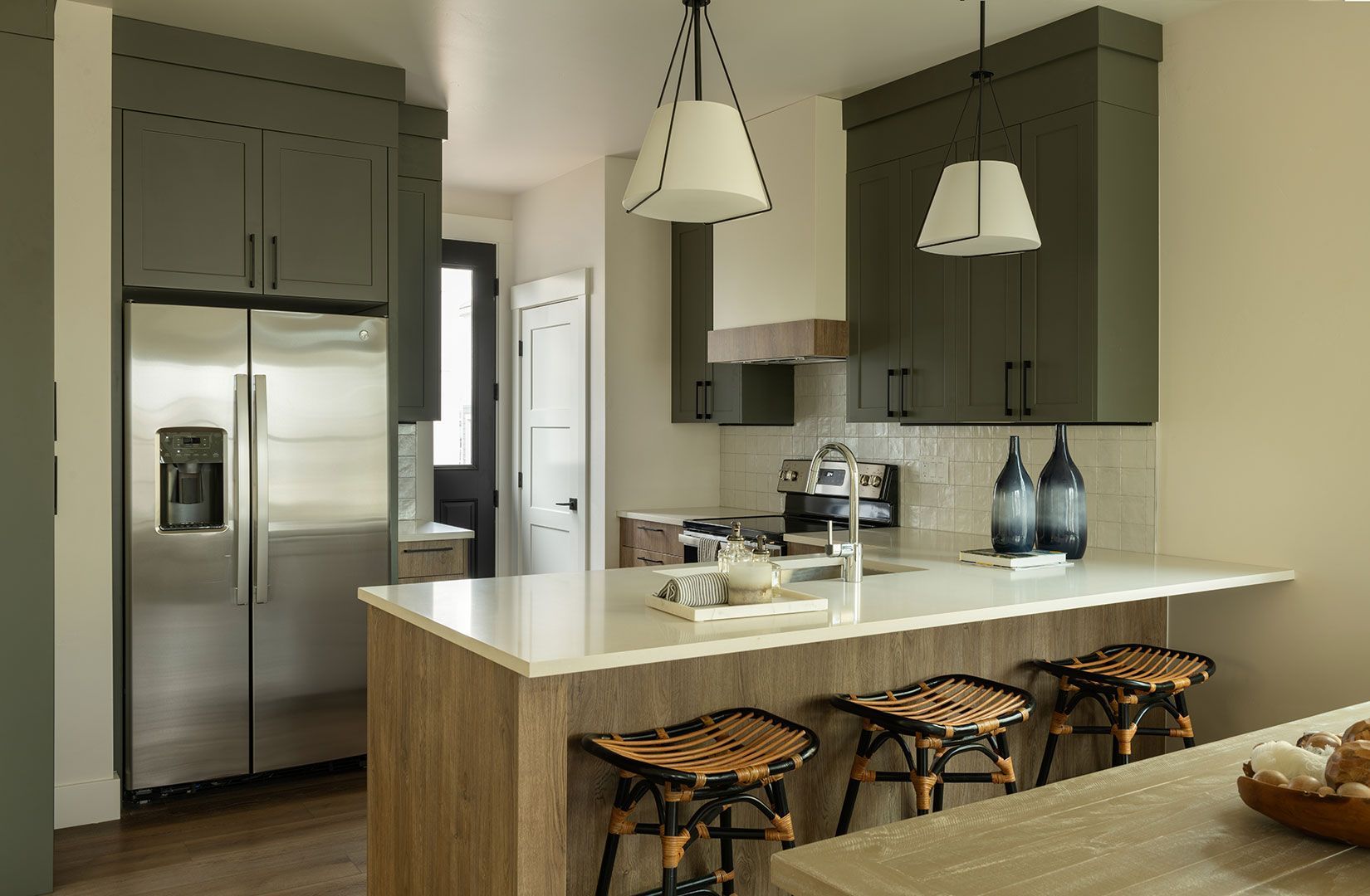 A kitchen with stainless steel appliances, a refrigerator, a sink, and a large island.