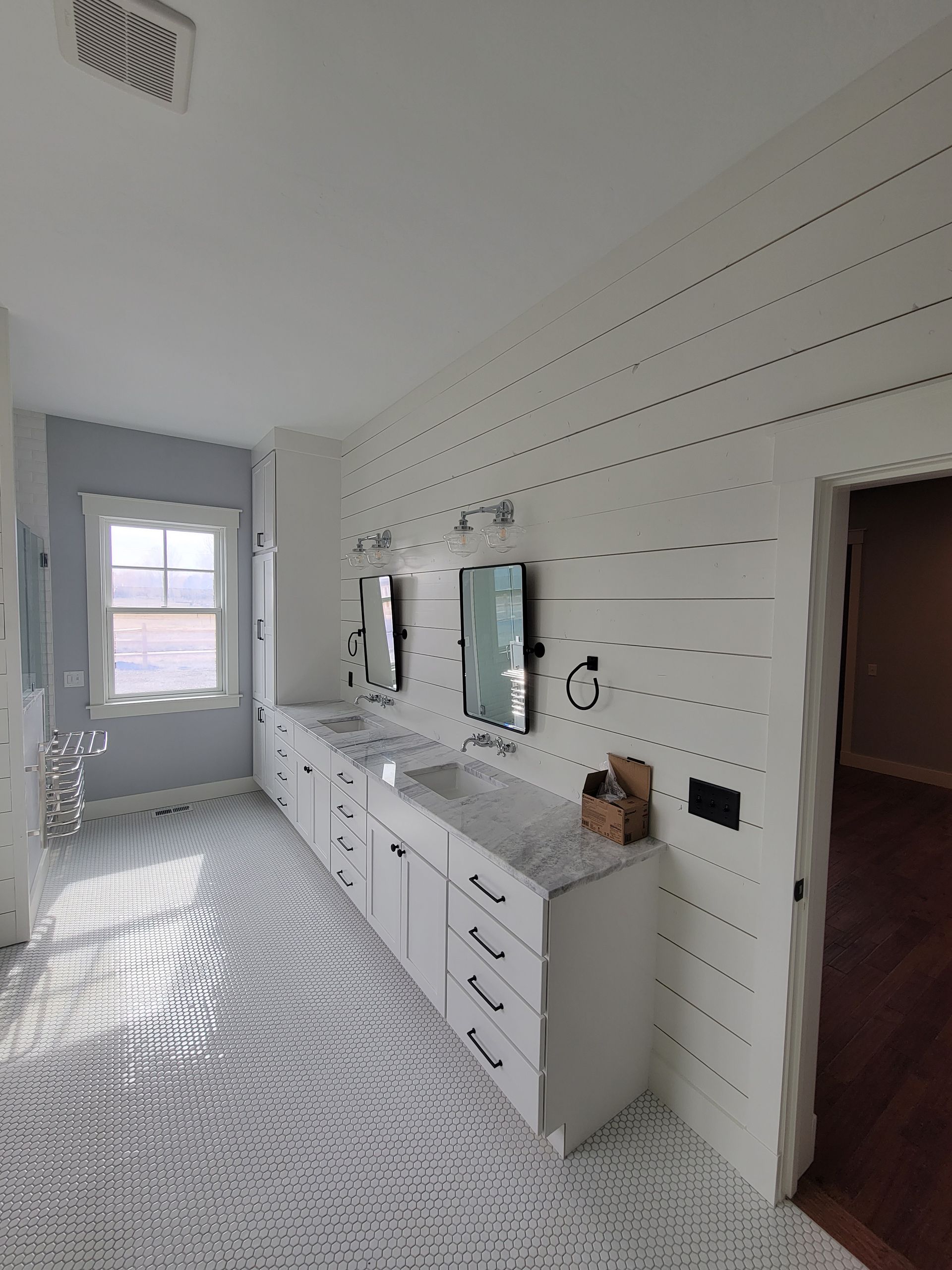 A bathroom with two sinks, two mirrors and a window