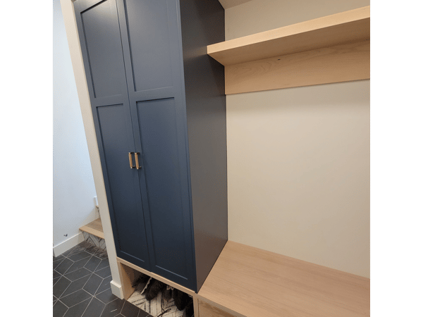 A blue cabinet with wooden shelves and a bench in a mud room