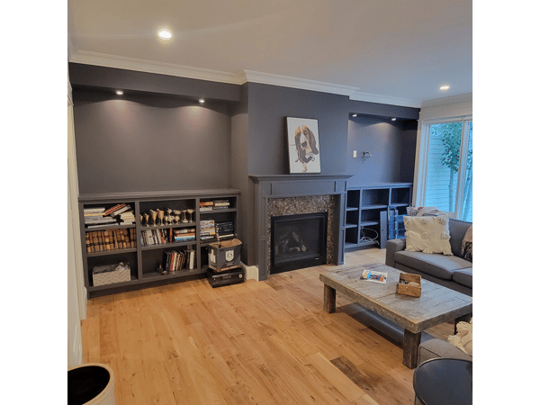 A living room with a fireplace, couch, coffee table and shelves