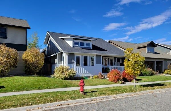 A white house with a fire hydrant in front of it in a residential neighborhood