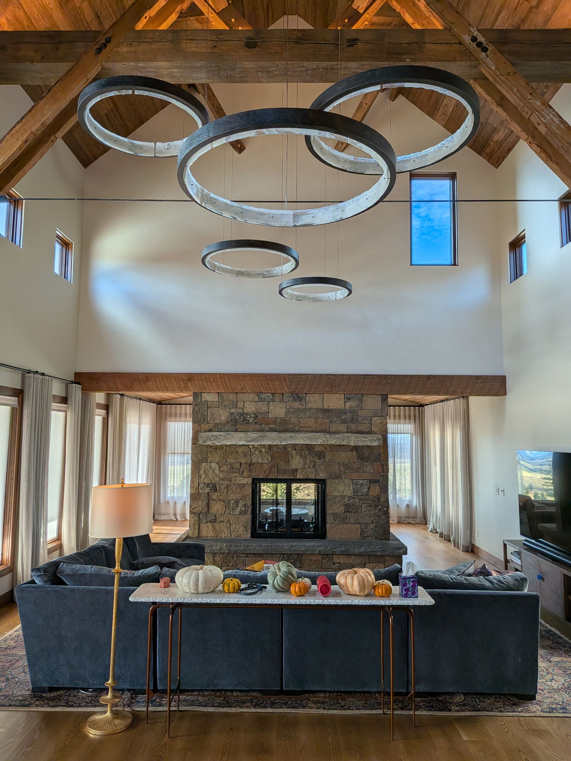 Living room with stone fireplace, dark blue sofa, and large circular hanging lights.