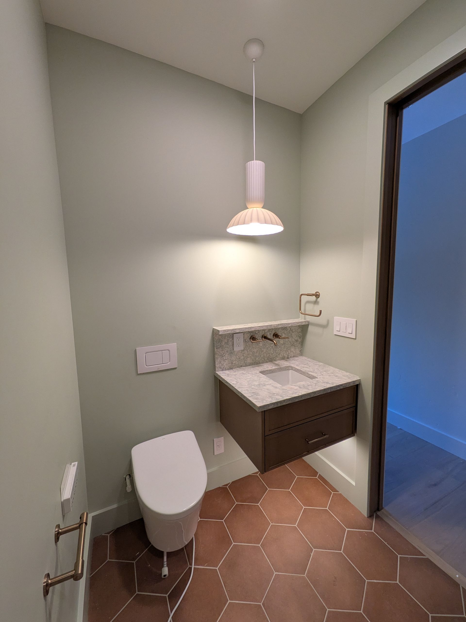 Small bathroom with a toilet, floating vanity, and hexagon tile floor.