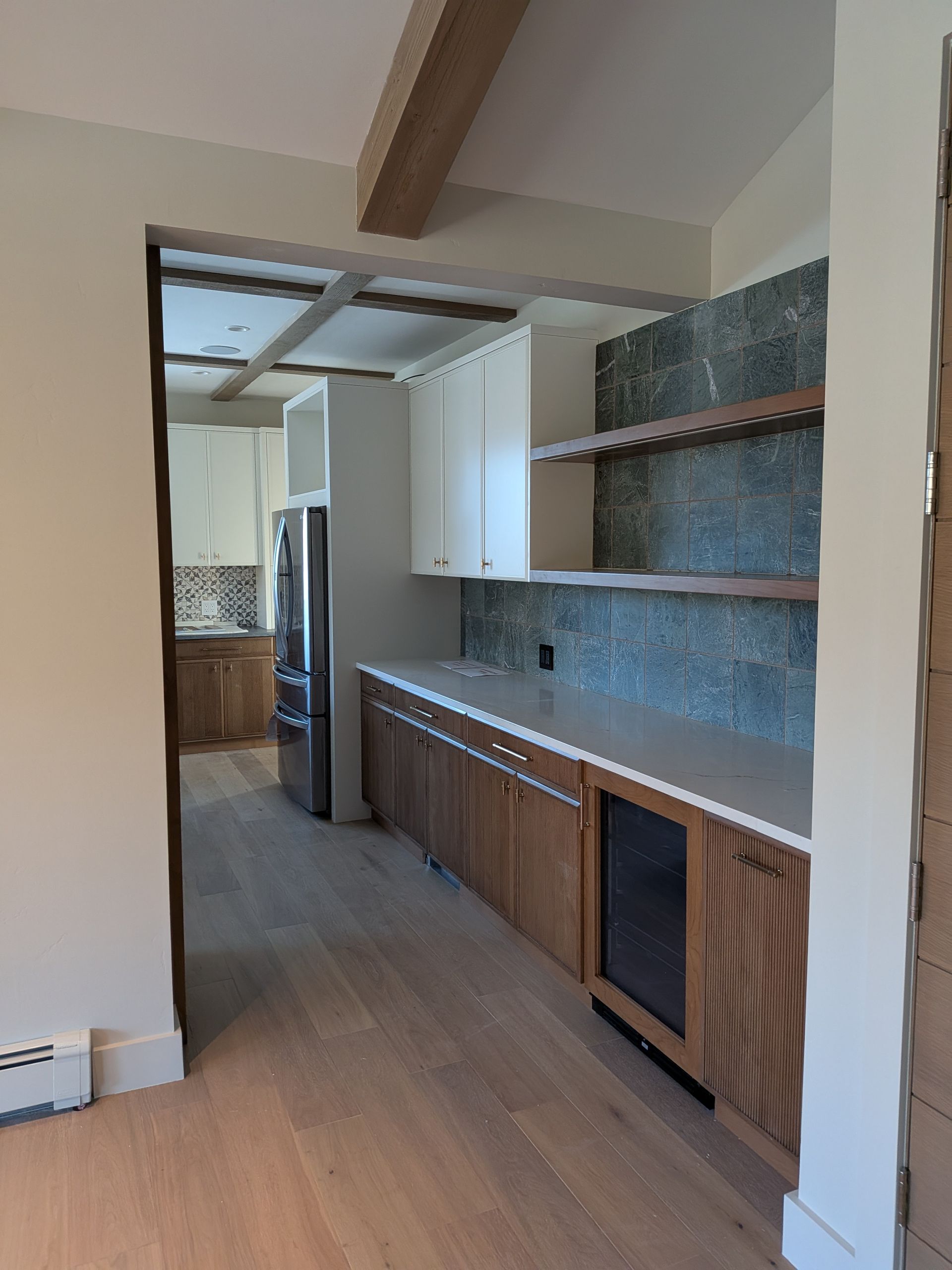 Kitchen with light wood cabinets, gray tile backsplash, and a wine fridge.