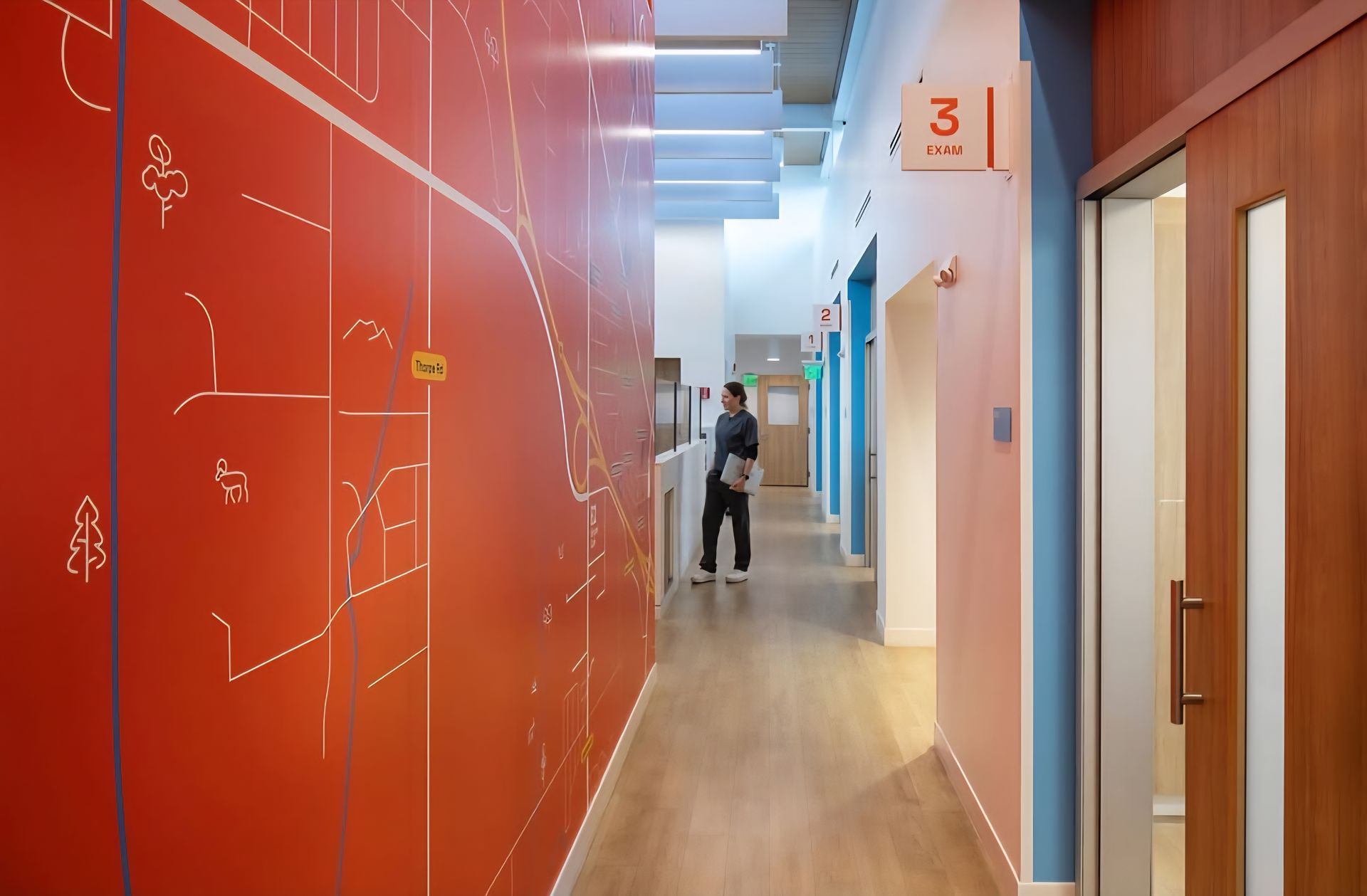 A man is walking down a hallway with a map on the wall.