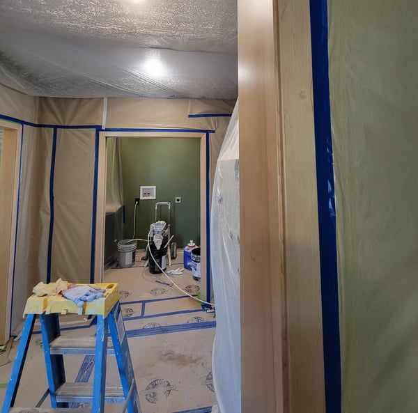 A room that is being painted with a ladder in the foreground