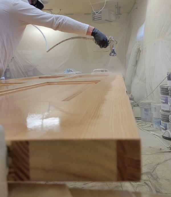 A man is spraying paint on a piece of wood.