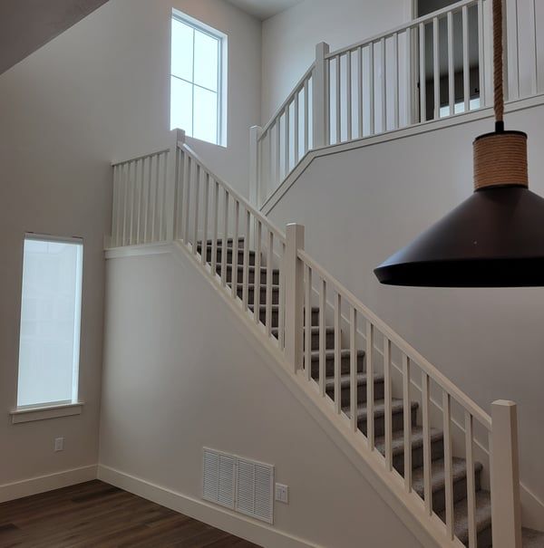 A white staircase with a black lamp hanging from the ceiling