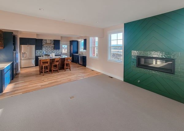 A living room with a fireplace and a kitchen in the background.