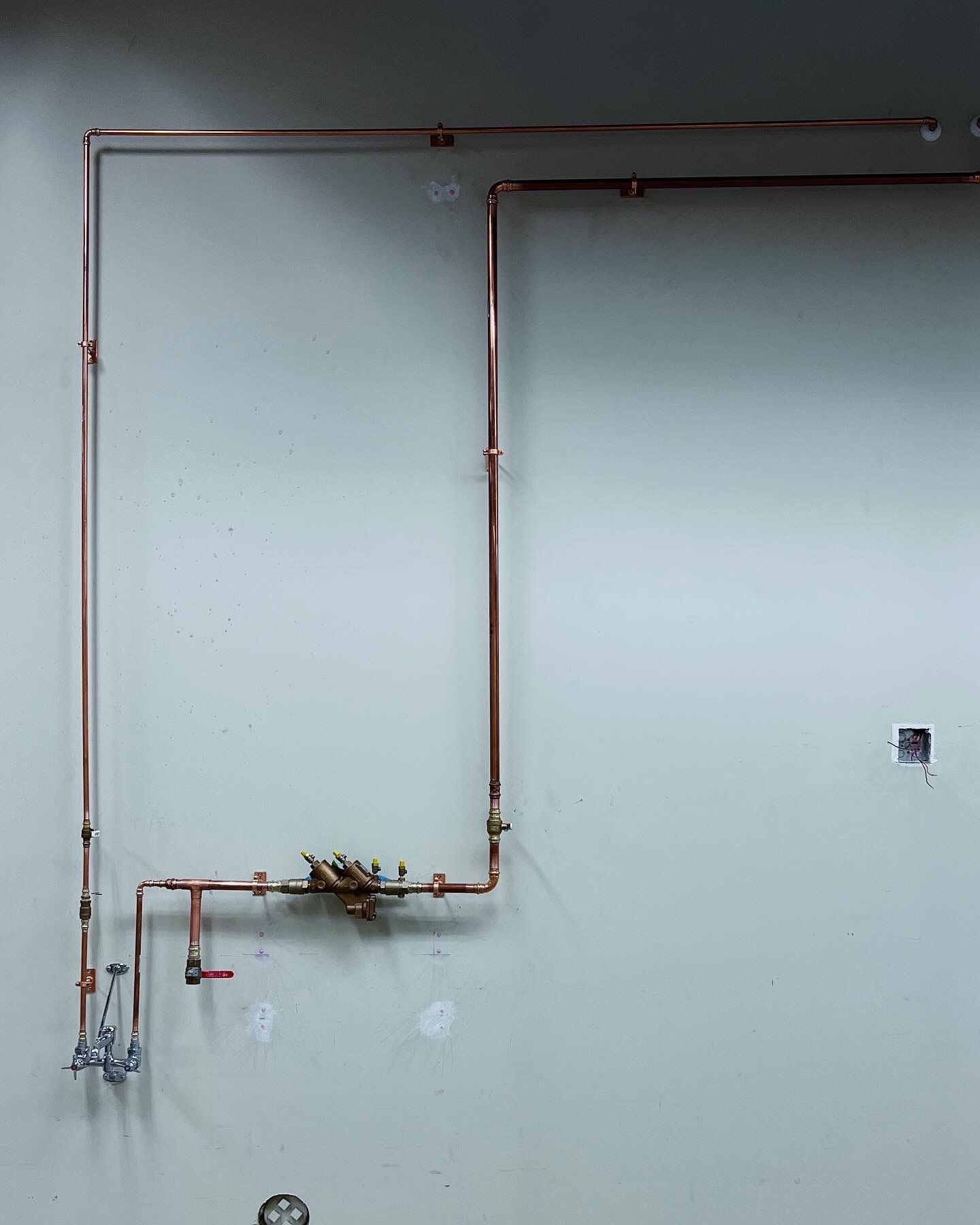 A copper pipe is hanging on a white wall.