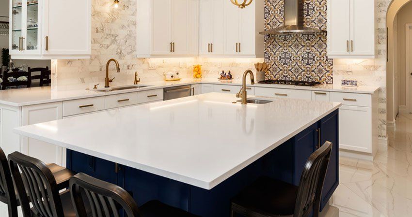 Modern kitchen with white countertops and blue island.
