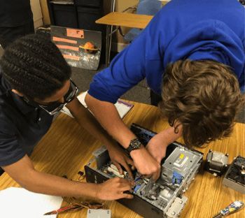 Two young men are working on a computer on a table