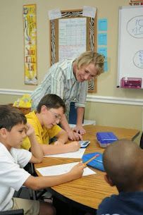 A teacher is helping a group of children with their homework in a classroom.