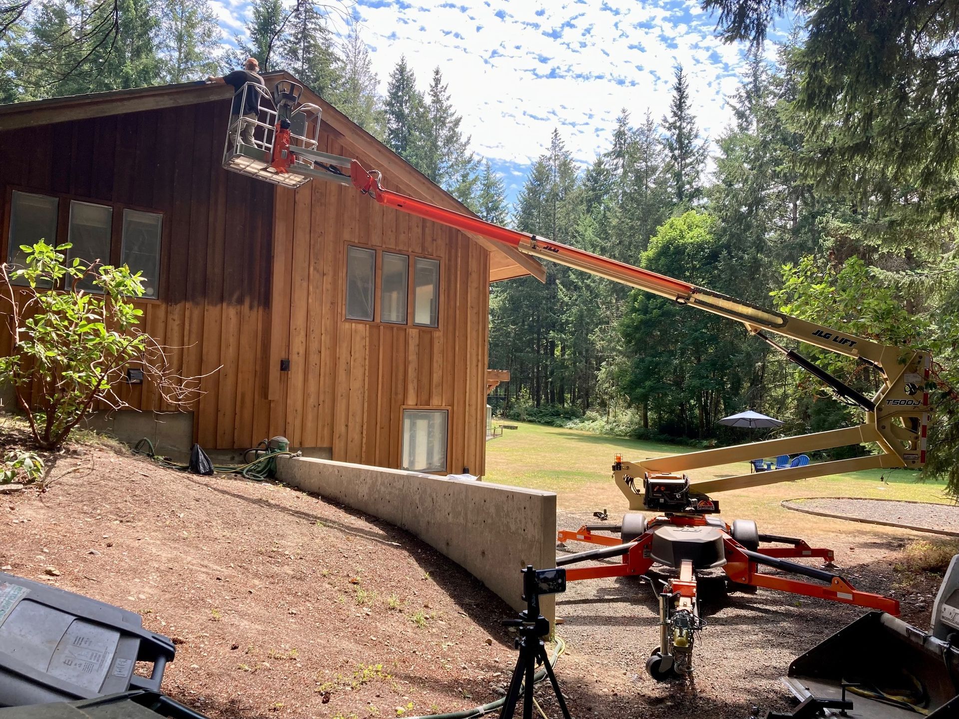 House being worked on with an extended lift; a person is high up, near the roof.