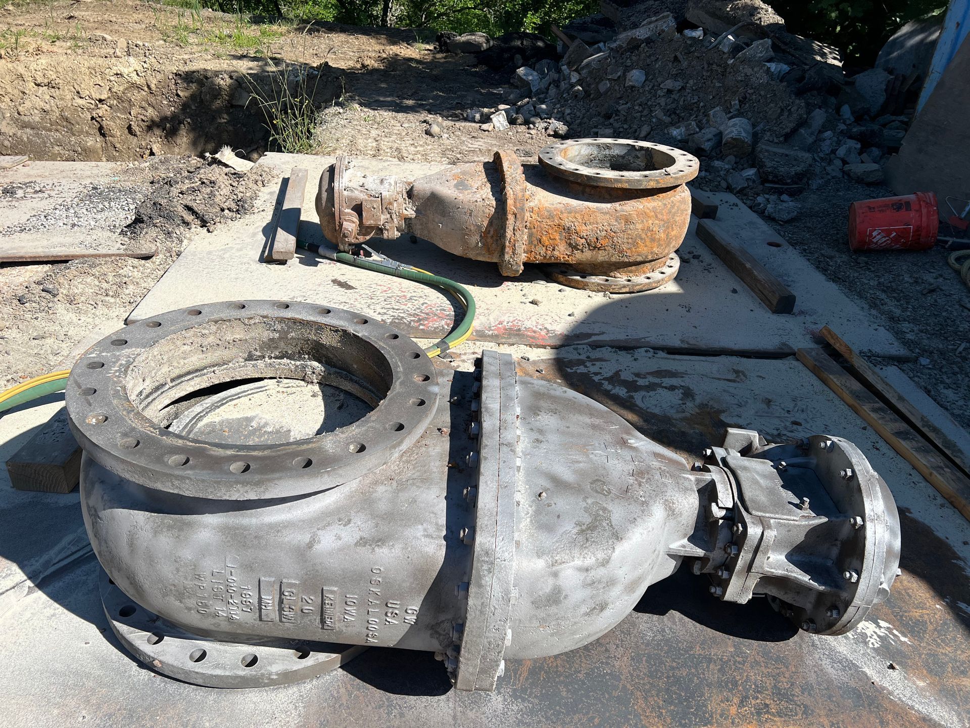 Two large, metal pump casings; one old and rusted, the other newer and gray, on a concrete surface.