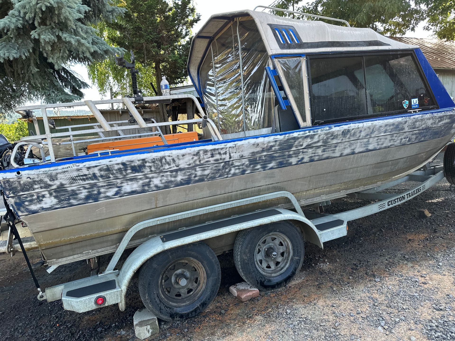 Boat on a trailer with a blue and silver cabin. Metal frame in back.