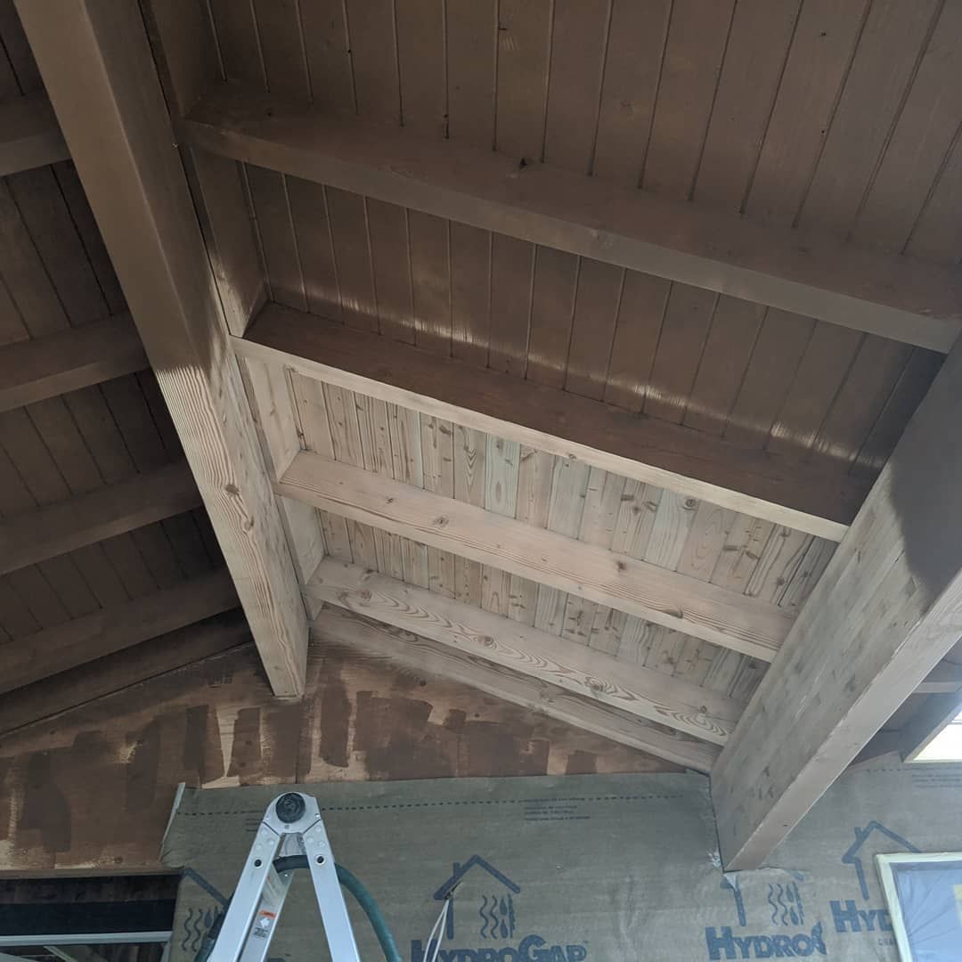 Wooden ceiling with exposed beams, ladder in front of a wall.