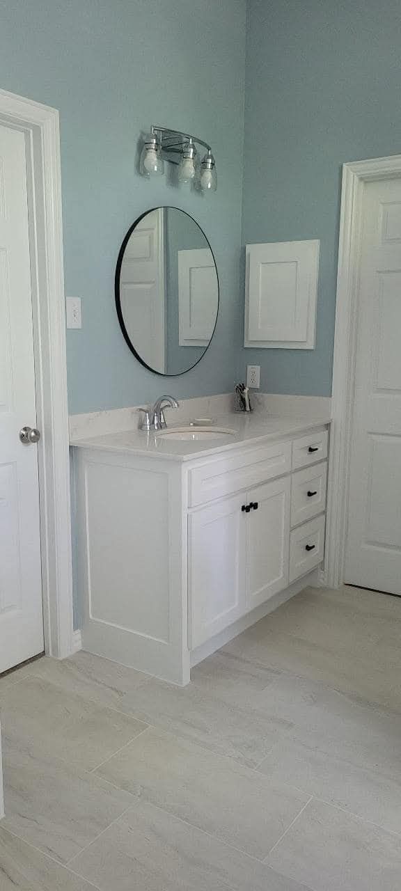 A bathroom with a sink , mirror and light fixture