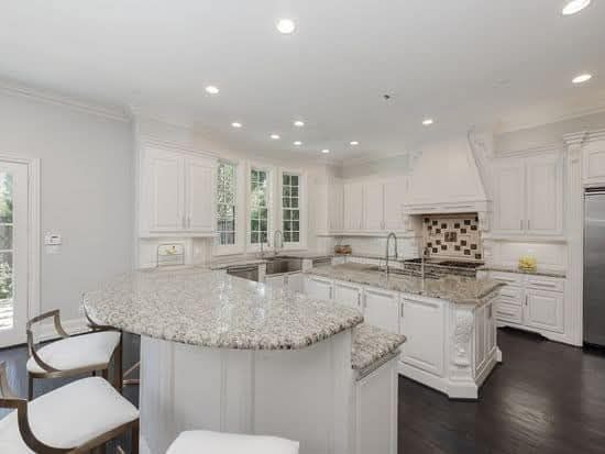 A kitchen with white cabinets , granite counter tops , and stainless steel appliances