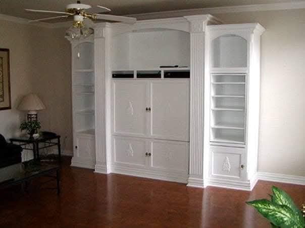 A living room with white cabinets and a ceiling fan