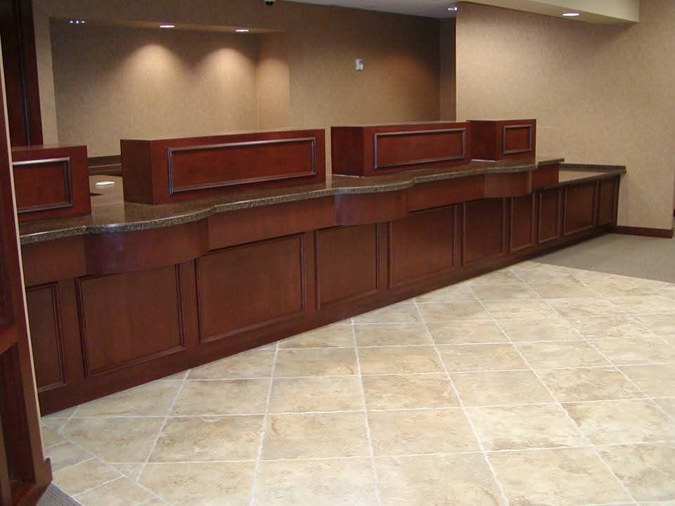 A long wooden counter in a bank with a tiled floor