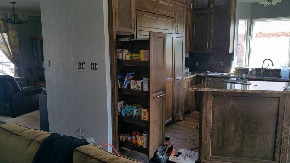 A kitchen with a pantry and a couch in the background